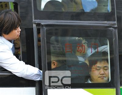 售票员用手将门口的乘客往里推，以便车门能顺利关上。