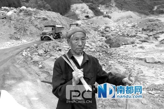 老人身后,小木岭沿途堆积的泥石流已经填平河道,并高出路面。