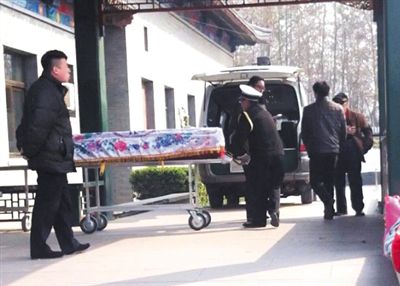 3月25日，东郊殡仪馆。一辆遮挡号牌的“黑殡仪车”停在院内，工作人员抬下逝者。