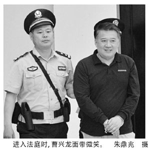 曹兴龙被押上法庭时仍然面带笑容。